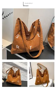 Vue détaillée du sac cabas en velours côtelé marron avec broderie blanche et texture douce