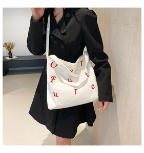 Gros plan du sac cabas en velours côtelé blanc avec broderie Future rouge et texture