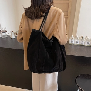 Large black suede tote bag with long shoulder strap and side pocket in casual setting