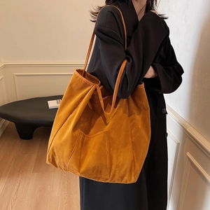 Minimalist orange suede tote bag with front pocket shown on model in modern studio