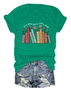 Flat lay of green t-shirt with book floral print and distressed denim shorts