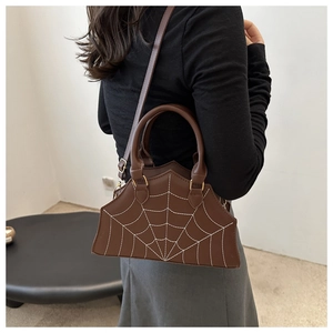 Detail of dark brown handbag with white spider web embroidery and sturdy handle