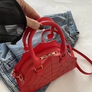 Detail of red crossbody bag with black spider web pattern and wavy edge design