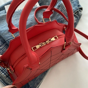 Close-up of red spider web quilted handbag with gothic bat wing design and gold hardware
