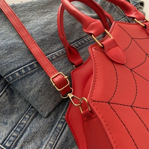 Detail of red PU leather handbag with black spider web stitching and gold metal hardware