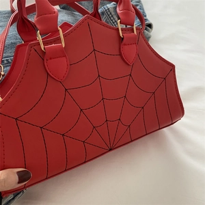 Macro shot of red spider web handbag showing fine stitching and gold metal hardware