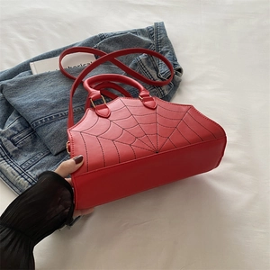 Detail of red leather bag featuring black spider web stitching and golden hardware