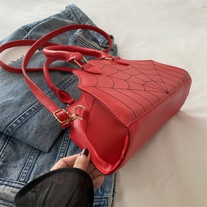 Detail shot of red spider web pattern handbag with black stitching and gold hardware