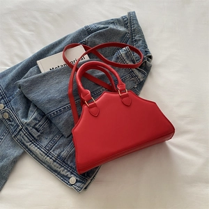 Detailed top view of a red structured handbag with gold hardware on denim background