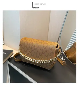 Detailed macro view of brown square crossbody bag with all-over M-letter logo and gold chain