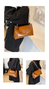 Close-up of brown glossy leather shoulder bag with silver bow detail and chain strap