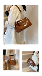 Close-up of brown patent leather tote bag featuring a metallic bow and gold chain strap
