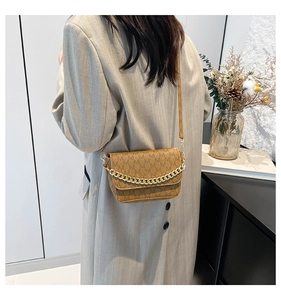 Detail of brown flap bag with M-letter monogram print and chunky metal chain decoration
