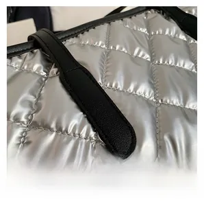 Détail du sac argenté matelassé avec surpiqûres en losange et bandoulière noire