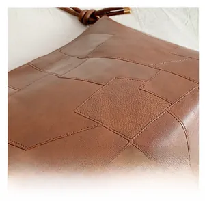 Detail of brown leather hobo bag featuring stitched patchwork design and gold hardware
