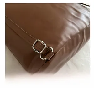 Detail of silver metal adjustment buckle on dark brown leather shoulder bag strap