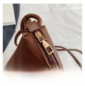 Detail shot of smooth gold-tone metal zipper on dark brown lychee pattern leather tote