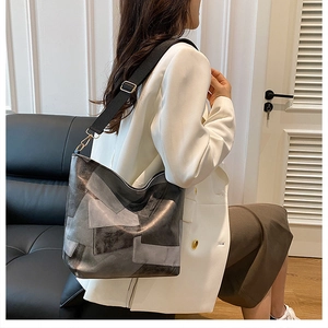 Close-up of a large grey bucket bag with patchwork design and black shoulder strap