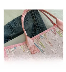 Détail d'un sac cabas rose gaufré avec broderie zigzag multicolore et poignée tissée