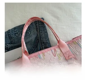 Détail du sac cabas rose montrant la texture jacquard et les broderies ondulées colorées