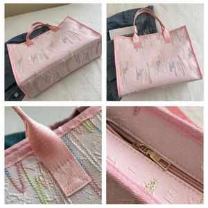 Détail du sac cabas rose montrant la texture brodée, les anses et la fermeture éclair
