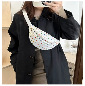 Close-up of a white canvas fanny pack with colorful polka dots and adjustable strap