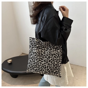 Chic leopard print canvas tote bag with slim black handles shown on a model