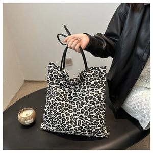 Detailed view of leopard print tote bag featuring sturdy black straps and metal rings