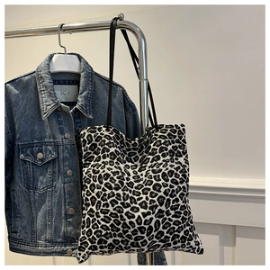 Detail of leopard print tote bag texture with slim leather shoulder strap and metal rings