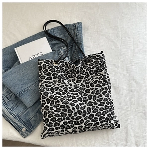 Détail du cabas en toile à imprimé léopard avec bandoulières sur fond de denim