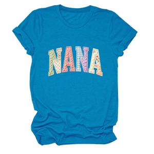 Détail d'un t-shirt bleu vif avec des lettres NANA en patchwork floral multicolore brodé