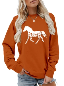 Detail of bright orange sweatshirt featuring white horse silhouette with floral textures