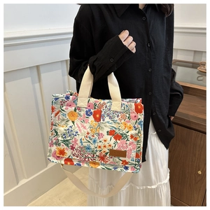 Close-up of floral canvas tote with adjustable strap and fashion leather patch detail