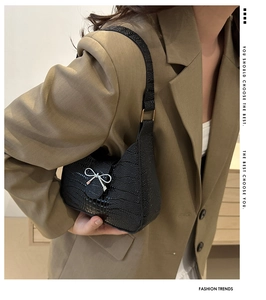 Détail du sac sous l'aisselle noir texturé avec un nœud métallique argenté sur la sangle