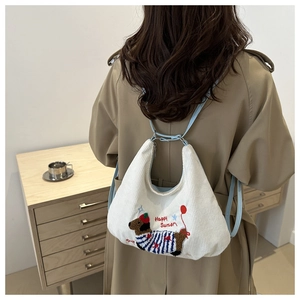 Detail of white corduroy backpack with blue straps and embroidered dachshund design
