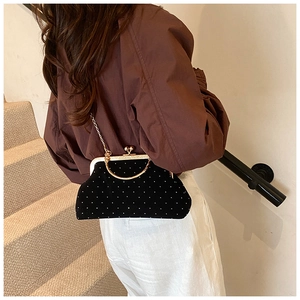 Detail of black velvet evening clutch featuring silver dots and a gold metal handle