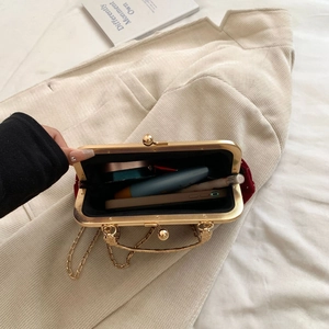 Detail view of red velvet evening bag capacity showing lipstick and phone inside