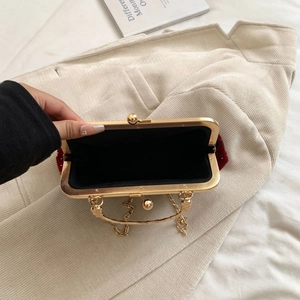 Macro view of burgundy velvet evening bag with gold metal clasp and beaded details
