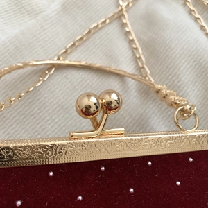 Close-up of vintage burgundy velvet evening bag with ornate gold floral frame and bead clasp