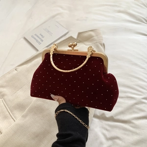 Detail of red velvet evening bag with pearls, gold clasp frame and ring handle