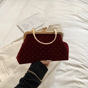 Close-up of burgundy velvet evening bag with pearls and gold metal handle