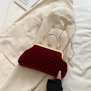 Detail of red velvet evening bag with white pearl beads and golden metal handle