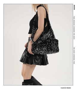 Detailed side view of a large black sequin hobo shoulder bag worn by a model in studio