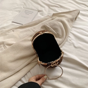 Detail of leopard print spherical evening bag with rhinestone ring handle and gold chain