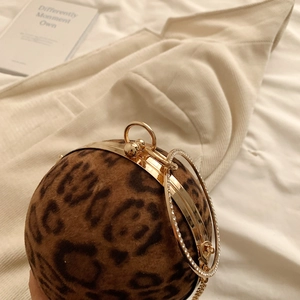 Detailed macro view of a leopard print spherical bag with golden handle and diamond ring