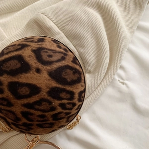 Macro view of leopard print plush sphere bag with elegant gold metal trim and chain