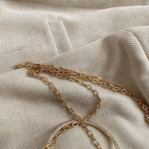Detail of gold multilayer metal chain with a diamond-encrusted ring on corduroy