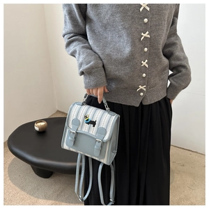 Détail d'un sac à dos à rayures bleues avec rabat en cuir et broderie de chien