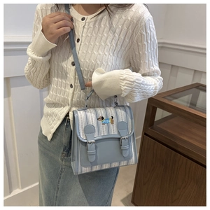 Detail of light blue striped backpack featuring embroidery and vintage leather straps