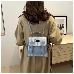 Mini striped backpack with cartoon dog embroidery shown on model in beige trench coat